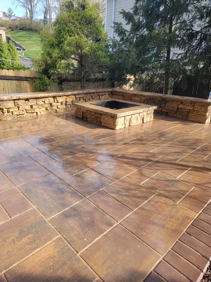 Square stone fire pit and low stone wall on a tiled patio