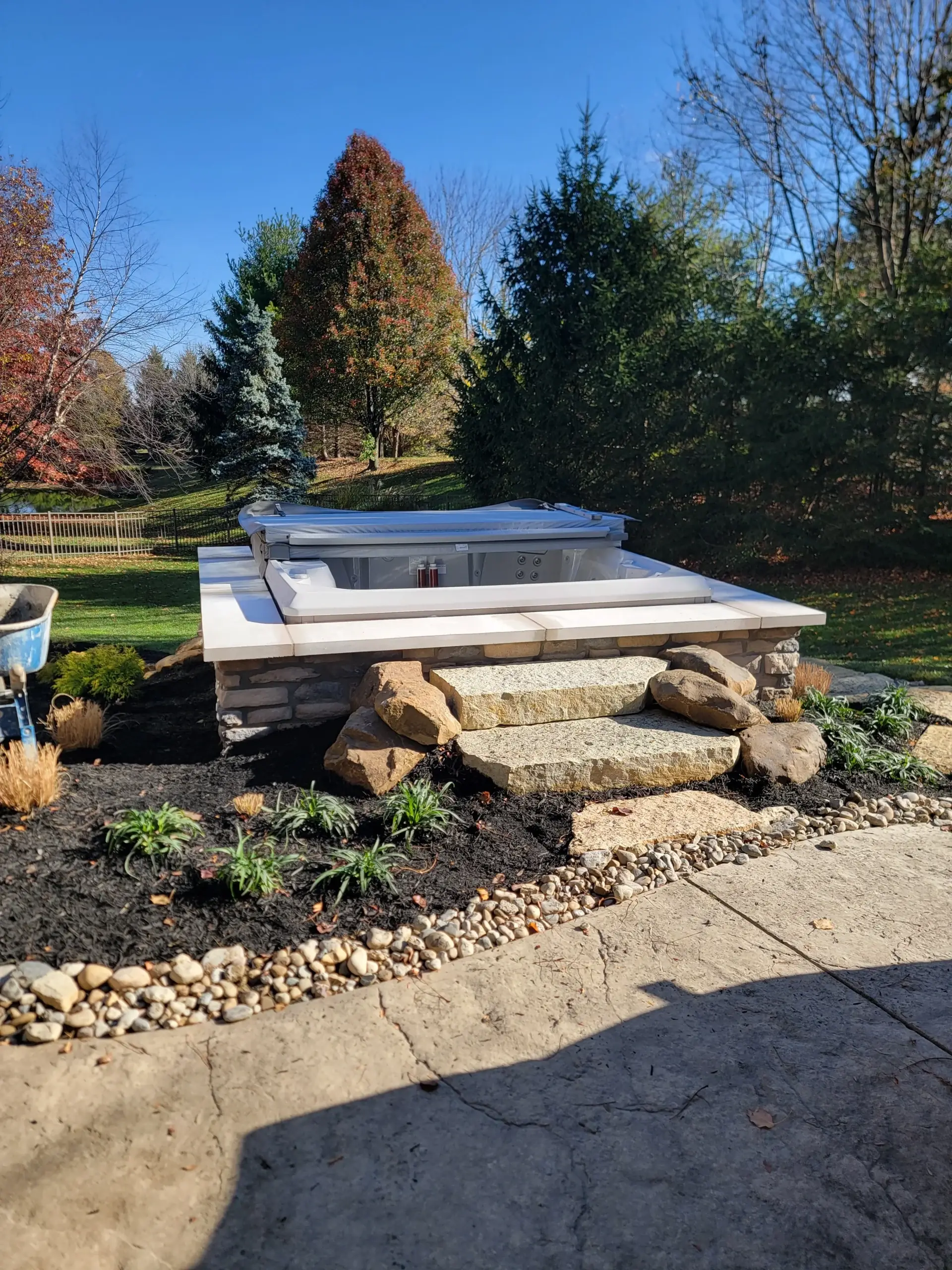 Hot tub on a raised stone platform with steps and plantings