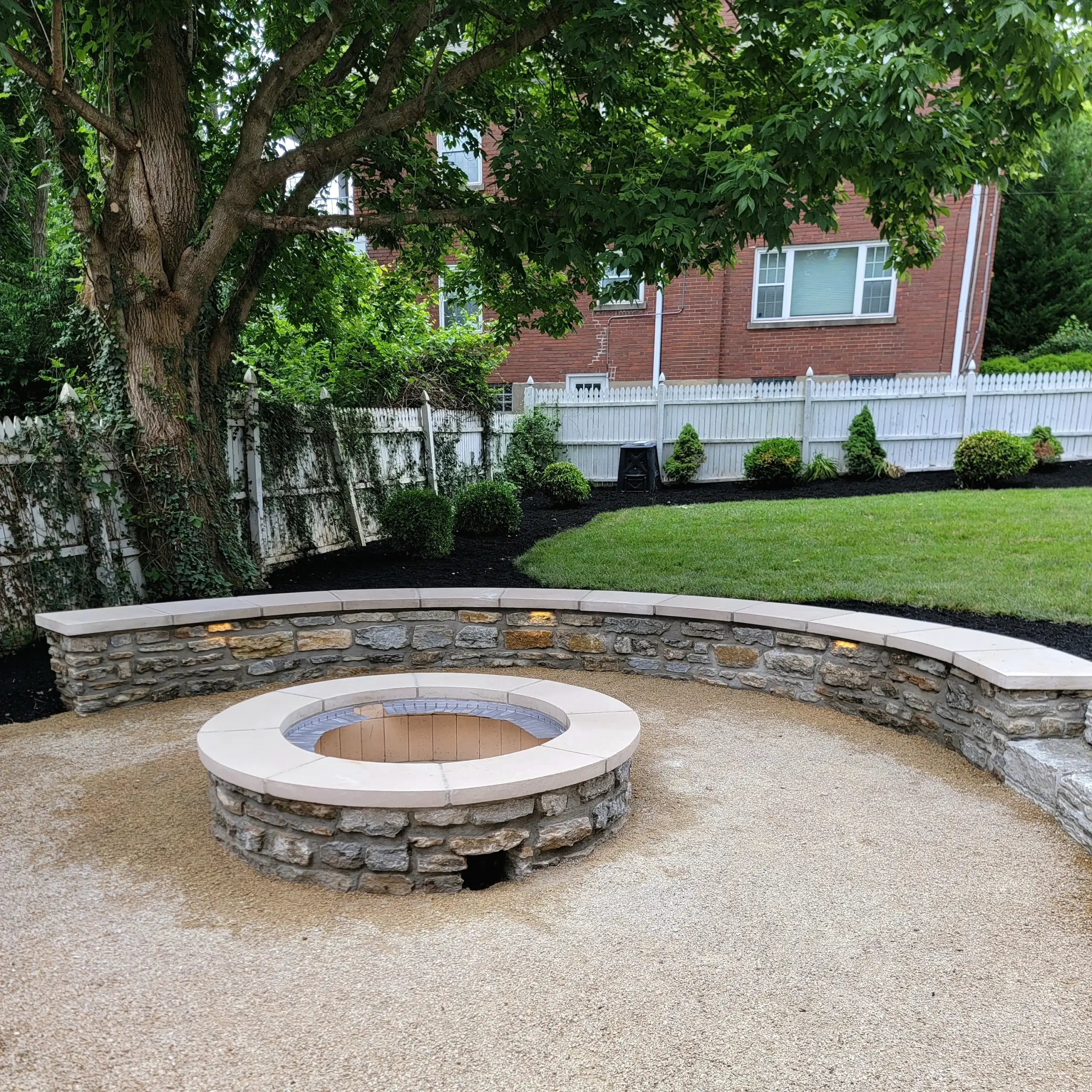Stone fire pit and curved stone seating wall on a backyard patio